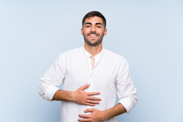 Wall Mural - Handsome man with beard over isolated blue background smiling a lot