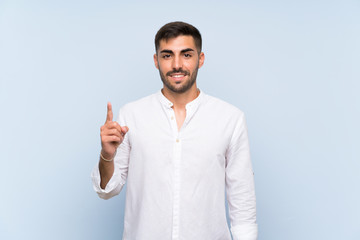 Wall Mural - Handsome man with beard over isolated blue background showing and lifting a finger in sign of the best