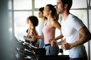 group of young people running on treadmills in modern sport gym