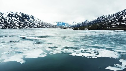 Wall Mural - frozen lake with pieces of ice floating at the surface, cold mountain landscape with snow in arctic 