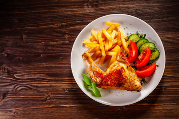 Top view of roast chicken leg with french fries and vegetable salad 