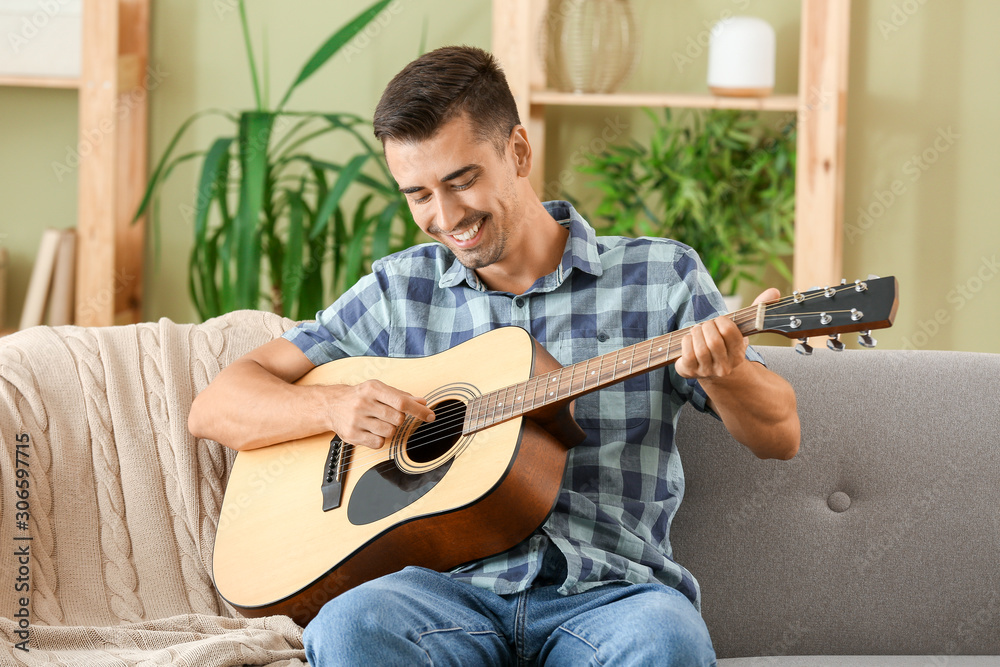 Handsome man playing guitar at home