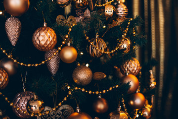 Wall Mural - Fir branch with golden balls and festive lights on the dark background with sparkles.