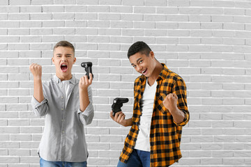 Wall Mural - Teenager boys playing video games against grey brick background