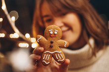 Selective Focus, Noise Effect: Merry Christmas And Happy New Year! Christmas Cookies, Gingerbread Man Figure Holding A Smiling Woman In Her Hands
