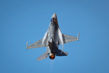 Extremely Close View Of A F-16 Fighting Falcon In A High G Turn, With Condensation Streaks At The Wing Roots, With Afterburner On 