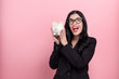 © Tierney - Young woman with a piggy bank on a pink background