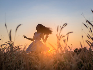 Wall Mural - Trendy girl in stylish summer dress feeling free in the field with flowers in sunshine.