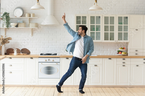 Cuadros en Lienzo Carefree funny young man having fun dancing alone in kitchen