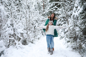 Young family for a walk. Mom and daughter are walking in a winter park.