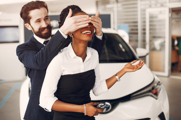 Couple buying the car. Lady in a car salon. Man in a suit