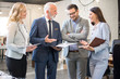 © Bojan - Mature and young businesswomen and businessmen standing in the modern office and analyzing business plan and strategy