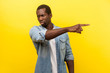 © khosrork - Get out! Portrait of irritated angry man in denim casual shirt pointing sideways, ordering to leave, looking with annoyed dissatisfied expression. indoor studio shot isolated on yellow background