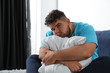 © New Africa - Depressed overweight man hugging pillow on bed
