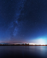 Wall Mural - A magical starry night on the river bank with a milky way in the sky and falling stars in the winter.