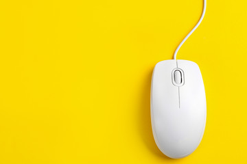 Modern wired optical mouse on yellow background, top view. Space for text