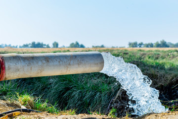 high pressure crystal bluish sweet water flushing out of an agriculture industrial tube waell in fields  