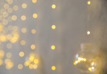 Blurred View Of Christmas Fairy Lights On Grey Wall. Interior Decoration