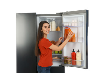 Canvas Print - Young woman taking juice out of refrigerator on white background