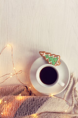 Wall Mural - mug with espresso and ginger Christmas tree, plaid and light garland on a table top view. coffee in the atmosphere of winter weekend