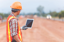 Asian Engineer With Hardhat Using Tablet Inspecting And Working At Construction Site