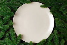 Top View Of Round Festive Plate On Fir Tree Background. Christmas Dish Concept With Empty Space For Your Design