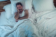 © TheVisualsYouNeed - dramatic lifestyle portrait of young attractive sad and depressed man lying on bed awake thinking at night feeling stressed suffering depression problem in sadness and melancholy