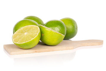 Group of four whole two halves of sour green lime on wooden cutting board isolated on white background