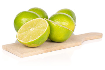 Wall Mural - Group of four whole two halves of sour green lime on wooden cutting board isolated on white background