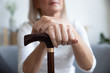 Closeup focus on female hands holding wooden walking stick cane