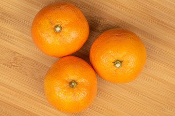 Poster - Group of three whole fresh orange mandarin flatlay on light wood