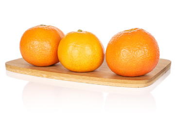 Group of three whole fresh orange mandarin on bamboo cutting board isolated on white background