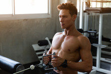 Handsome Muscular Fitness Man In The Gym, Training Hard And Pulling Weights In Seated Cable Row Machine, Athlete Makes Low Cable Pulley Row Seated In The Gym, Bodybuilder, Sport Fitness Concept