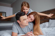 © alfa27 - lovely caucasian parents lying on bed with their kid girl, wearing casual clothes, happy smiling family together at home