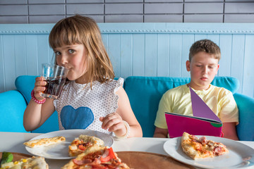 Wall Mural - Children eat in a cafe eat Italian pizza and drink cola.