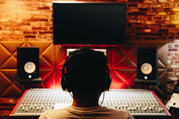 Wall Mural - back of asian male music producer working on audio mixing console in recording studio. music production, broadcasting, post production concept