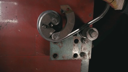 Forge workshop on table. Smithy manual production. Worker bends the metal rod on the wrought iron round bending machine. Manufacturing of a designer part from a metal rod. The blacksmith manufacture.