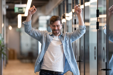 Excited businessmen celebrating career growth dancing in office hallway