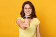 © sementsova321 - Studio shot of happy Caucasian woman holds take away cup of coffee or tea, having joyful facial expression, enjoying hot beverage, has coffee break, posing isolated over yellow studio background.
