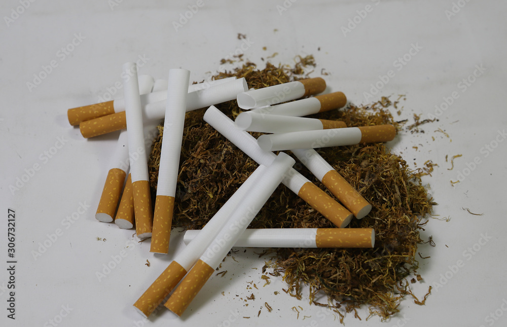 cigarette filters Empty cigarette paper top view Several black and white  cigarettes (tubes) with yellow filters, a handful of scattered tobacco.  Stock Photo