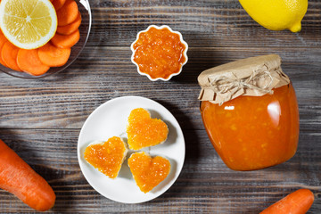 Wall Mural - Homemade carrot jam with lemon in a glass jar on a dark brown wooden background.