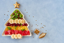  Christmas Background With Fruit Salad In Fir Tree Shaped Plate And Holiday Decoration. Top View Flat Lay