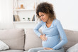 Pregnant afro woman having contraction at home