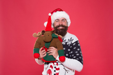 Wall Mural - Christmas prep concept. Hipster bearded face winter sweater. Kindness and charity. Winter holiday. Buy gifts. Winter sale. Winter feast. Reindeer toy. Man santa hat hold christmas gift red background