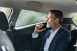 © Artem Varnitsin - Businessman holding a cell phone in the car while looking thoughtfully out of a window