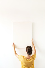 Young woman in yellow blouse hold blank canvas with empty mockup copy space. Minimal art concept.