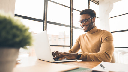 Satisfied african american manager typing on keyboard