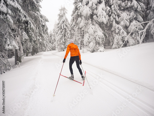 Plakaty biegi narciarskie  biegi-narciarskie-narciarz-biegowy-w-kolorze-pomaranczowym-jezdzi-na-nartach-w-zimowym-krajobrazie-rennsteig-las-turynski
