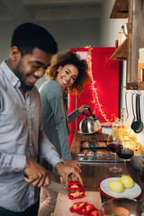 Happy african-american couple cooking dinner in kitchen