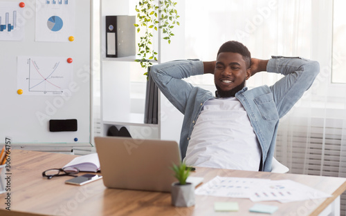 Fotomural Black businessman leaning back on chair in office after successful work